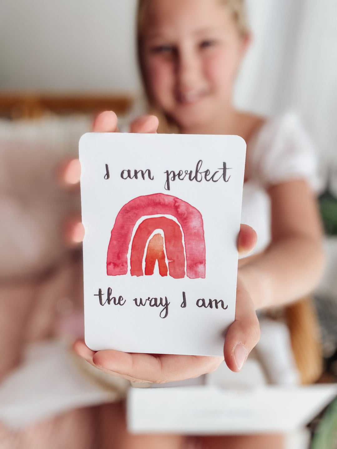 Young girl holding an affirmation card that says I am perfect the way I am