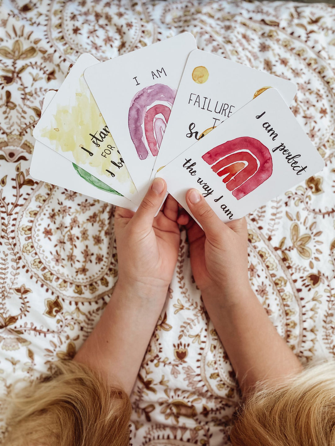 Kids affirmation cards splayed out in a young girls hands